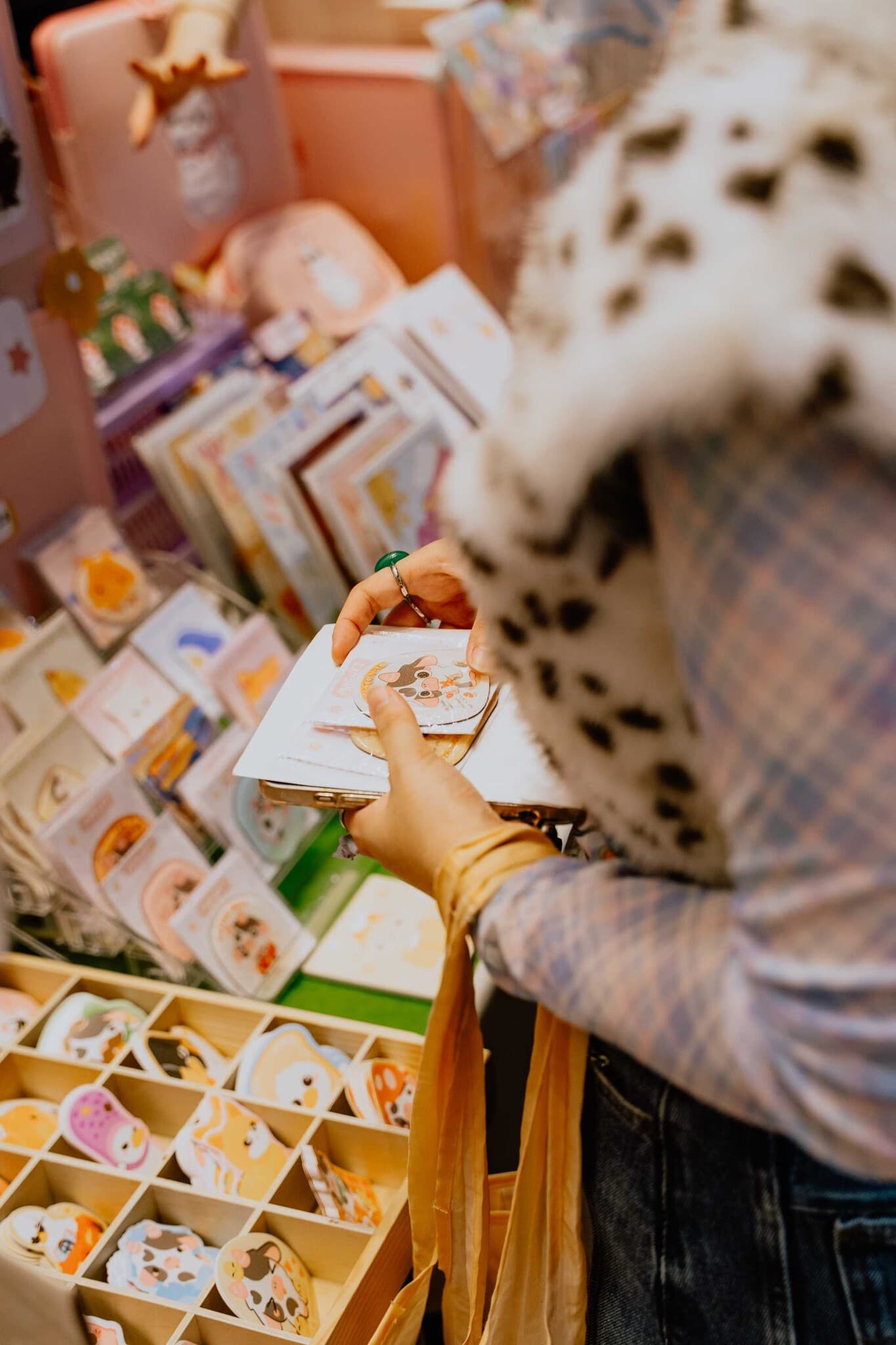 A shopper picking through trays of stickers and postcards