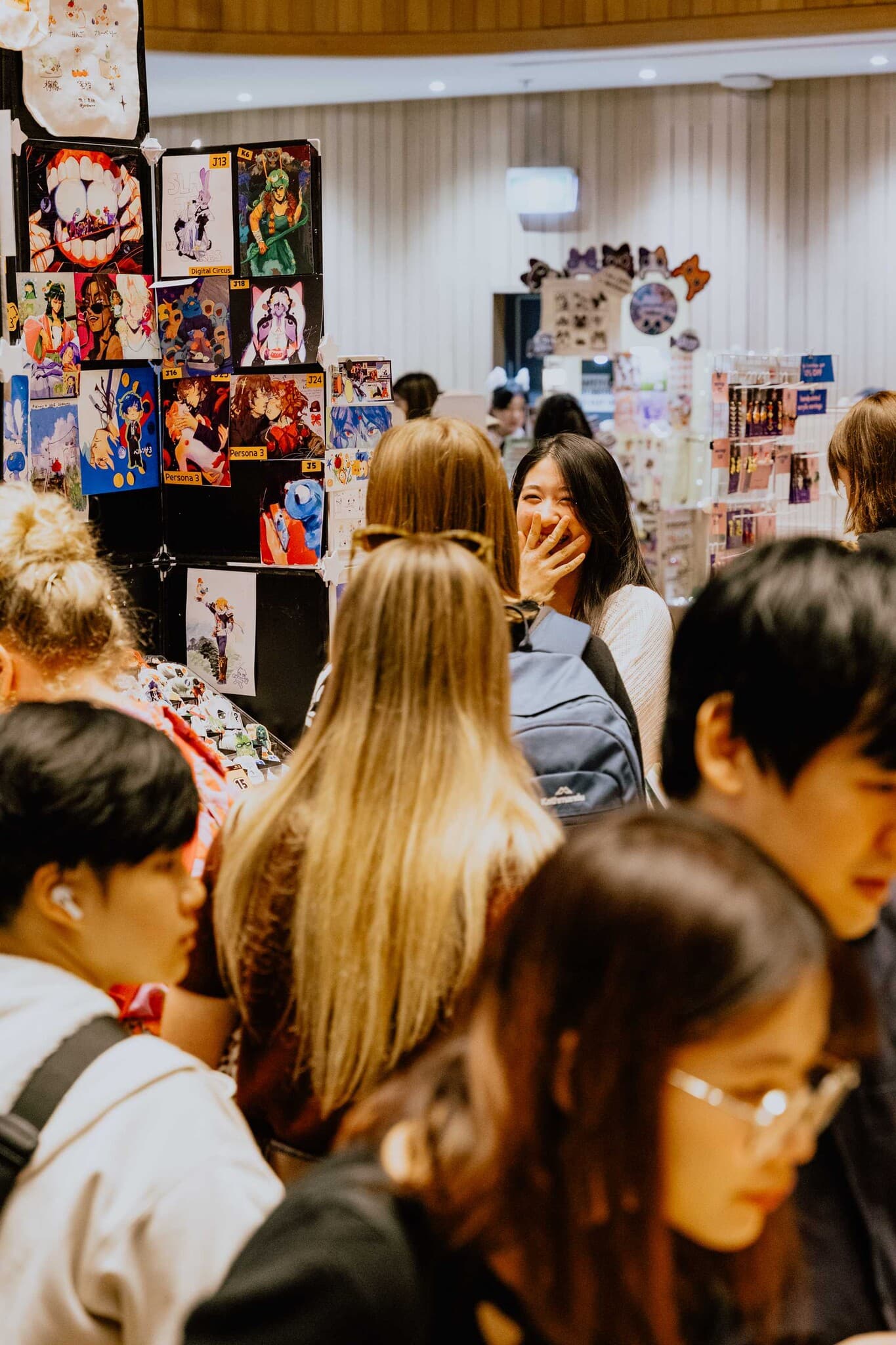 A lively crowd browsing a wall of art prints